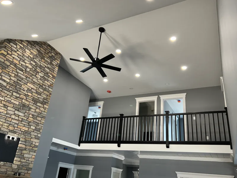 Recessed lighting installation in a vaulted great room with stone fireplace